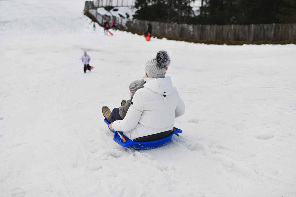 A Mother With Child Sledding In The Snow